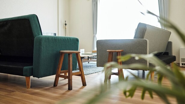 A modern living room with a dark green sofa, a grey armchair, and two wooden stools. - Fine court Yamahana (Sapporo)