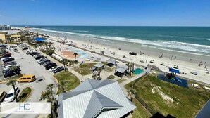 Une vue sur la plage, avec un parking, des parasols et un poste de surveillance pour les sauveteurs.