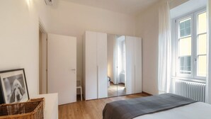 Ein Schlafzimmer mit Bett, Kleiderschrank, Fenster und Heizkörper.