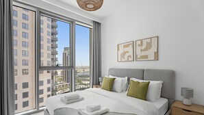 Une chambre d’hôtel moderne avec un grand lit, une vue sur la ville et des œuvres d’art accrochées au mur.