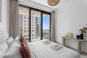 Een moderne hotelkamer met een groot bed, uitzicht op de stad en een klein bureau met een bloevas.