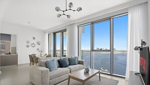 Un salon moderne avec un canapé, une table basse et une grande fenêtre donnant sur la mer.