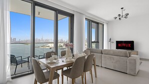 Un salon moderne comprenant un coin repas, de grandes fenêtres, un canapé et un téléviseur diffusant du contenu de « NETFLIX ».