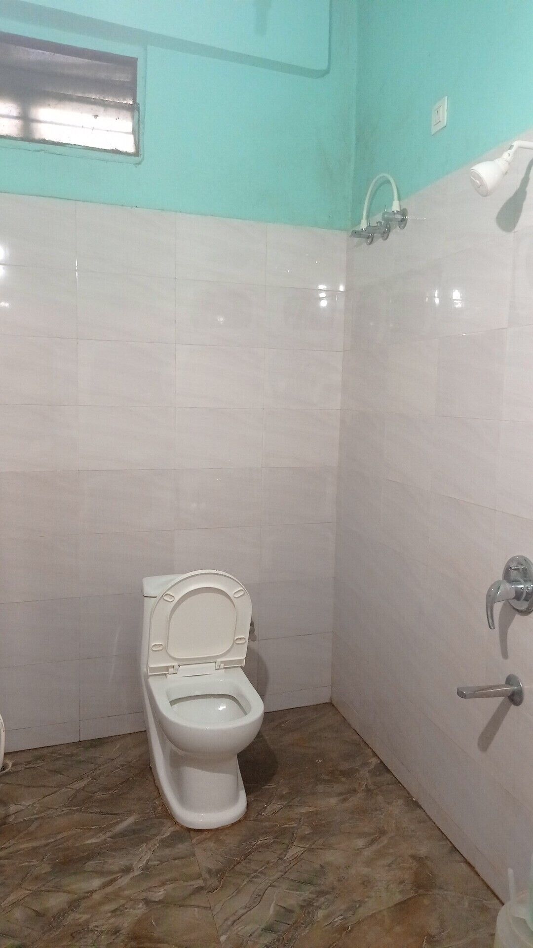 A small bathroom with a toilet, a shower, and a sink.