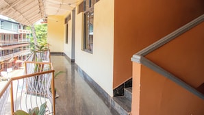 A corridor with a tiled floor, a railing, and a staircase. - Hotel Greens (Kumta)