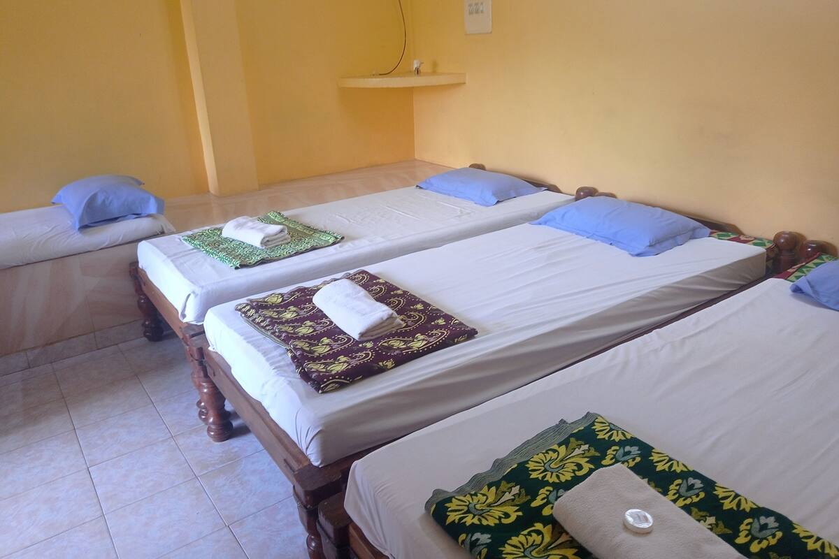 A hotel room with two single beds, each with a pillow and a folded towel.
