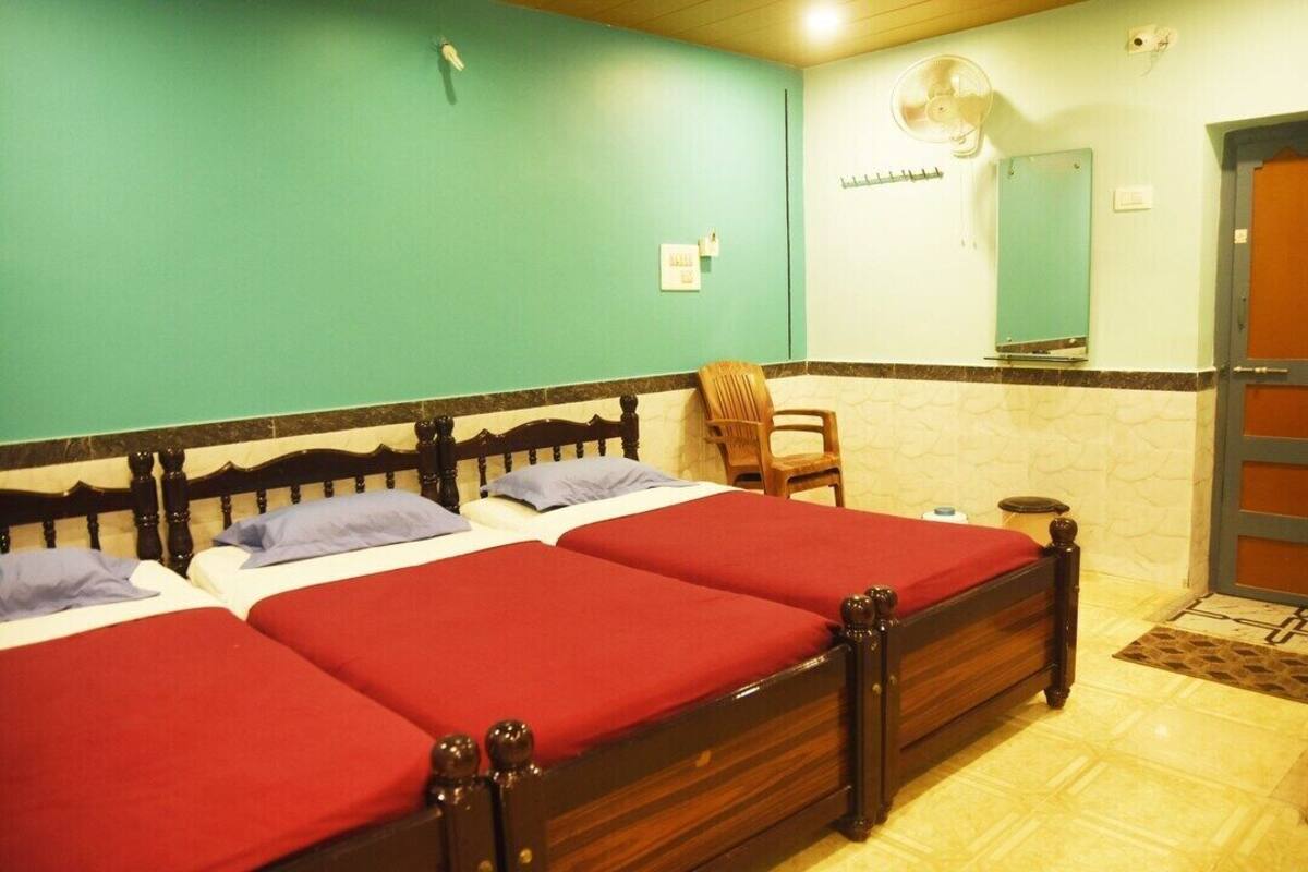 A room with three wooden beds, a chair, a small table, and a mirror on the wall.