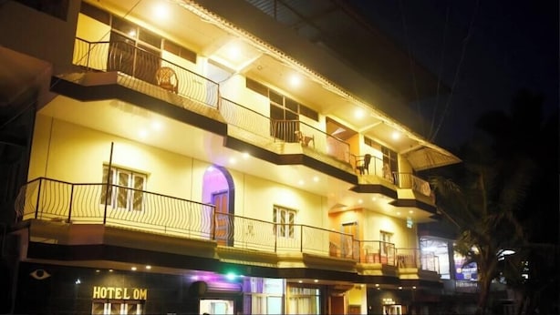 A multi-story hotel with balconies and a sign that reads "HOTEL OM". - Hotel Greens (Kumta)