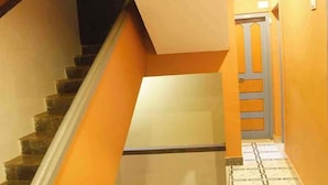 A staircase with orange walls and a tiled floor leading to a door. - Hotel Greens (Kumta)