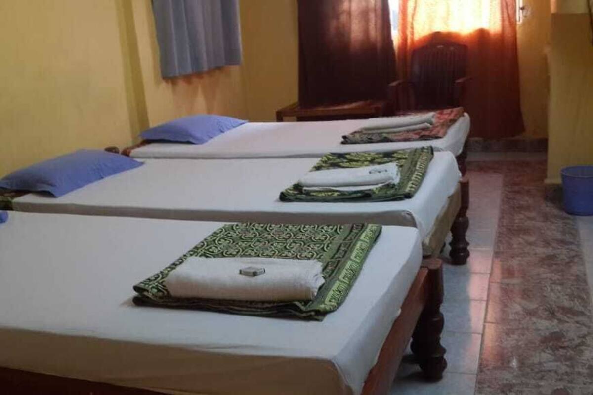 A room with two single beds, each with a pillow and a folded blanket.