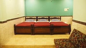 A room with a large bed, a sofa, and a green wall. - Hotel Greens (Kumta)