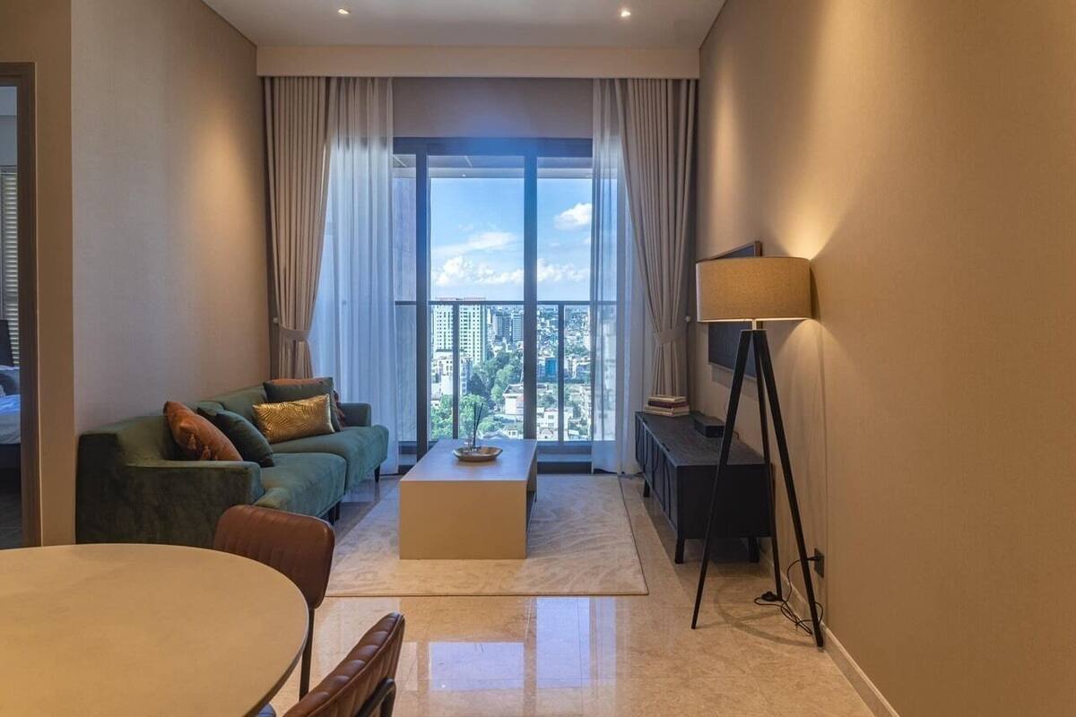 Ein modernes Wohnzimmer mit Sofa, Couchtisch und Blick auf eine Stadtlandschaft durch große Fenster.