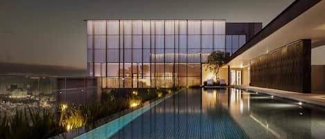 Un edificio moderno con una piscina reflectante y vistas a la ciudad.