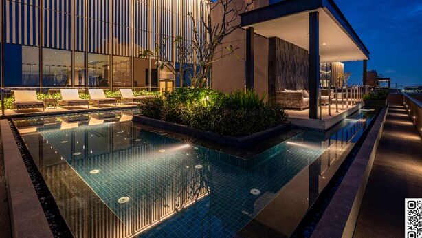 A modern building with a swimming pool, lounge chairs, and a covered seating area. - The MARQ  By An Gia Hospitality (Ho Chi Minh City)