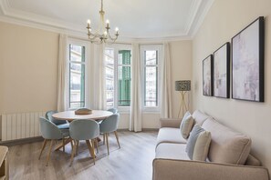 Uma sala de jantar com uma mesa redonda e cadeiras, um sofá e um lustre.