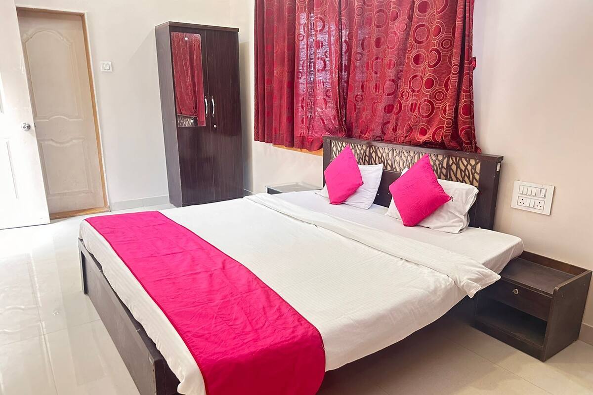 A neatly made bed with a white and pink bedspread, two pink pillows, and a wooden headboard.
