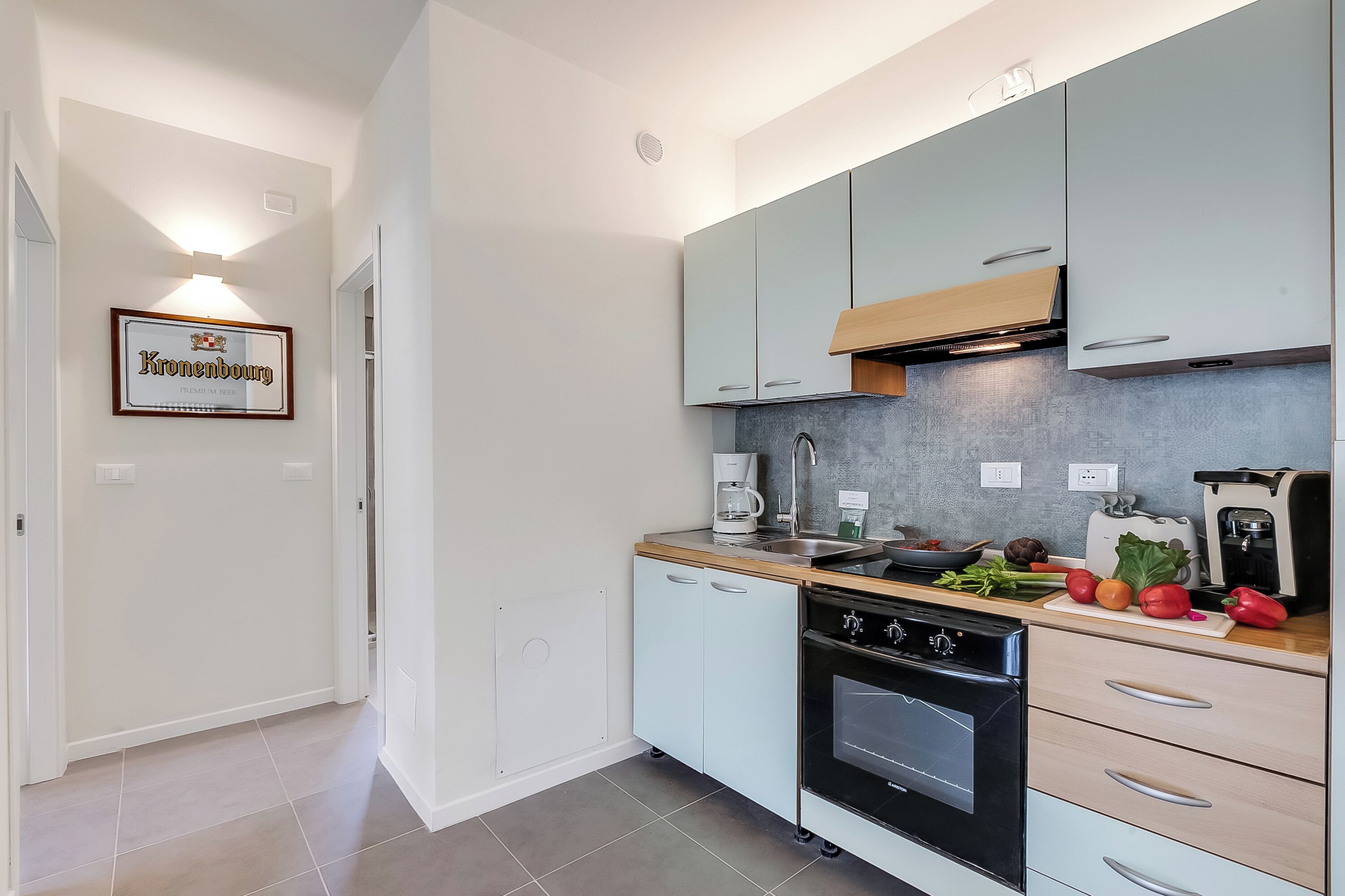 Une cuisine moderne avec des meubles de couleur bleu clair, un four noir et un plan de travail en bois.
