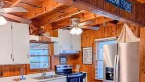 A wooden interior with a kitchen area, a dining table, and chairs.