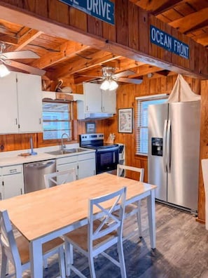 A wooden interior with a kitchen area, a dining table, and chairs. - Sammie's Retreat (Carolina Beach)