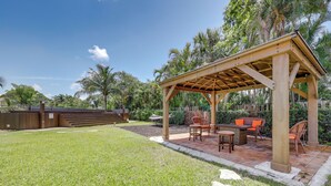 A covered outdoor seating area with a pergola, a fire pit, and a patio table with chairs. - Delray Beach Home w/ Pool ~ 4 Mi to Beach! (Delray Beach)