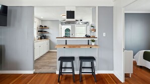 Una cocina moderna con una isla central, dos taburetes de bar y un horno empotrado.