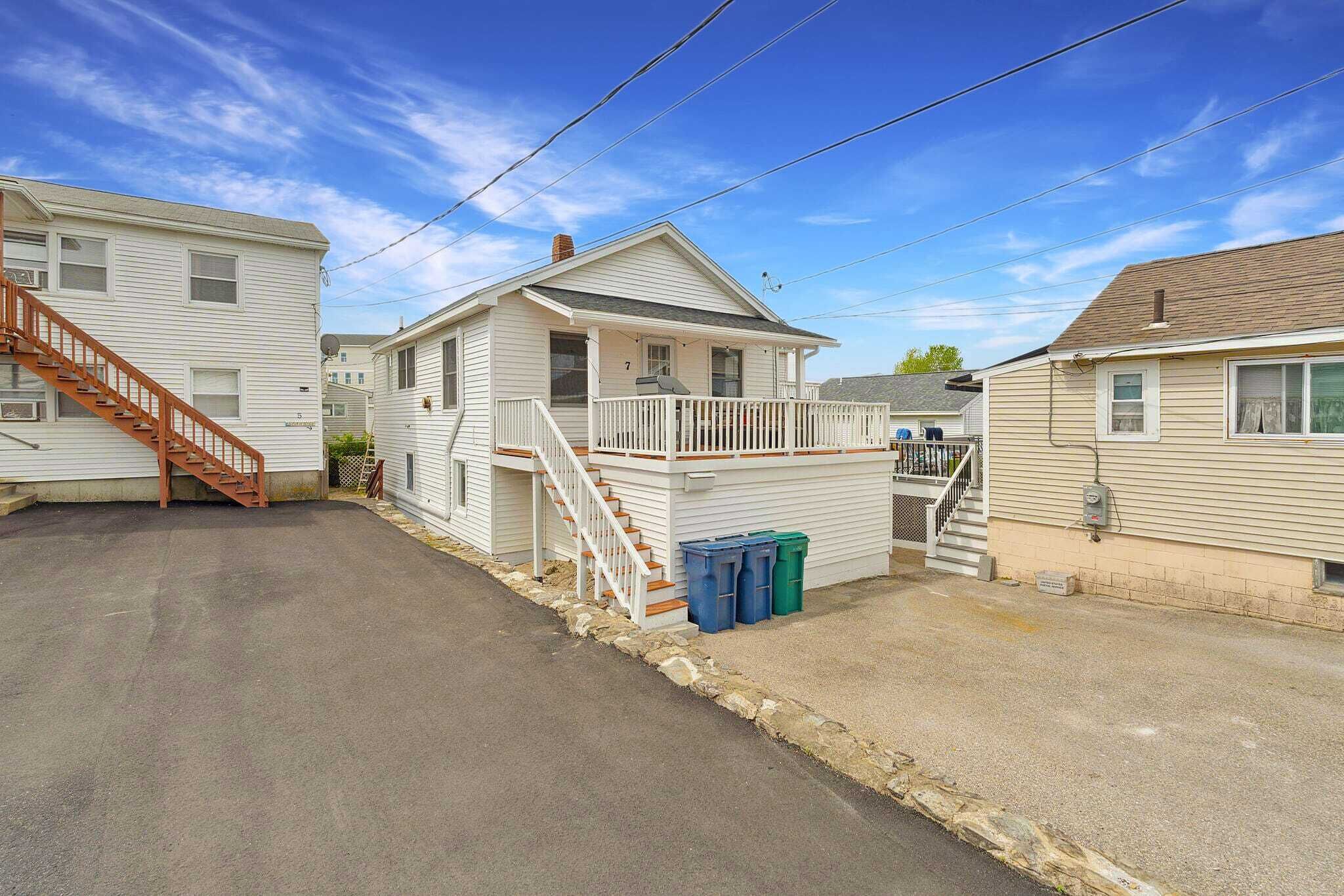 A row of mobile homes with a central house featuring a porch and a staircase.