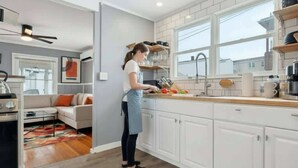 Una cocina moderna con armarios blancos, una encimera de madera y una persona preparando comida.
