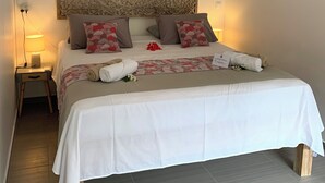 A neatly made bed with white linens, red and brown patterned pillows, and a decorative headboard.