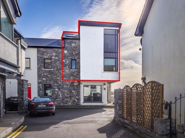 Un bâtiment moderne avec une façade en pierre, un toit plat et une grande fenêtre.