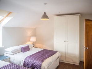 A bedroom with a bed, a wardrobe, a nightstand, a lamp, and a ceiling light. - Carraroe Apartment (Carraroe)