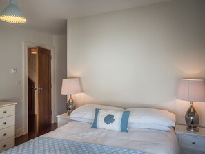 Ein Schlafzimmer mit einem Bett, zwei Nachttischlampen, einem Nachttisch, einer Kommode und einer Tür.