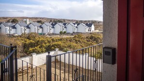 A row of white mobile homes with a gravel driveway and a metal railing in the foreground. - Carraroe Apartment ideal base to tour Connemara (Carraroe)