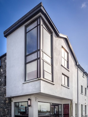 A modern building with large windows and a corner entrance. - Carraroe Apartment (Carraroe)