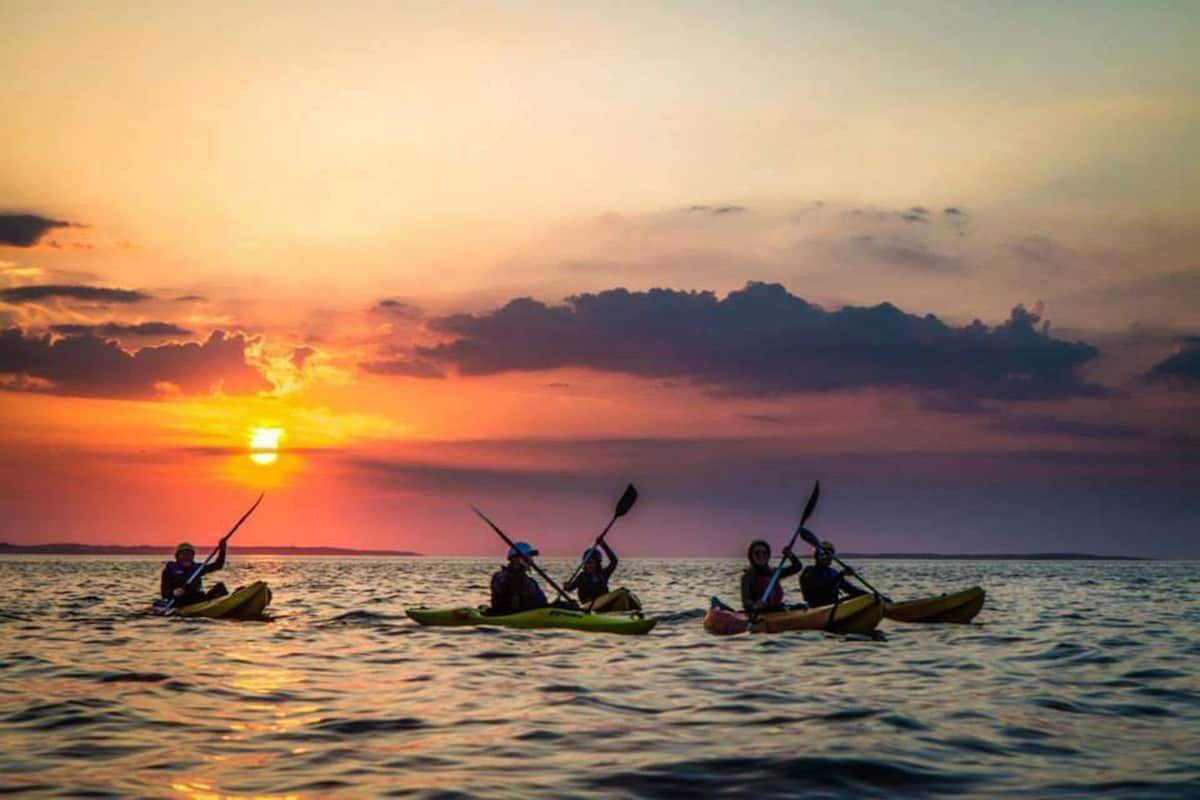 Tres kayak aigua tranquil·la al capvespre.