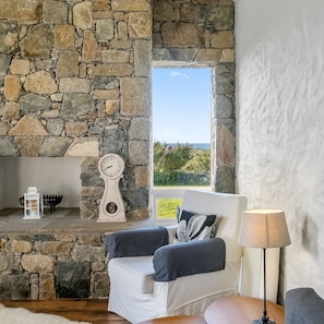 A stone-walled room with a white chair, a lamp, and a clock on a shelf. - Paddy Carroll´s, Ballyconneely (Ballyconneely)