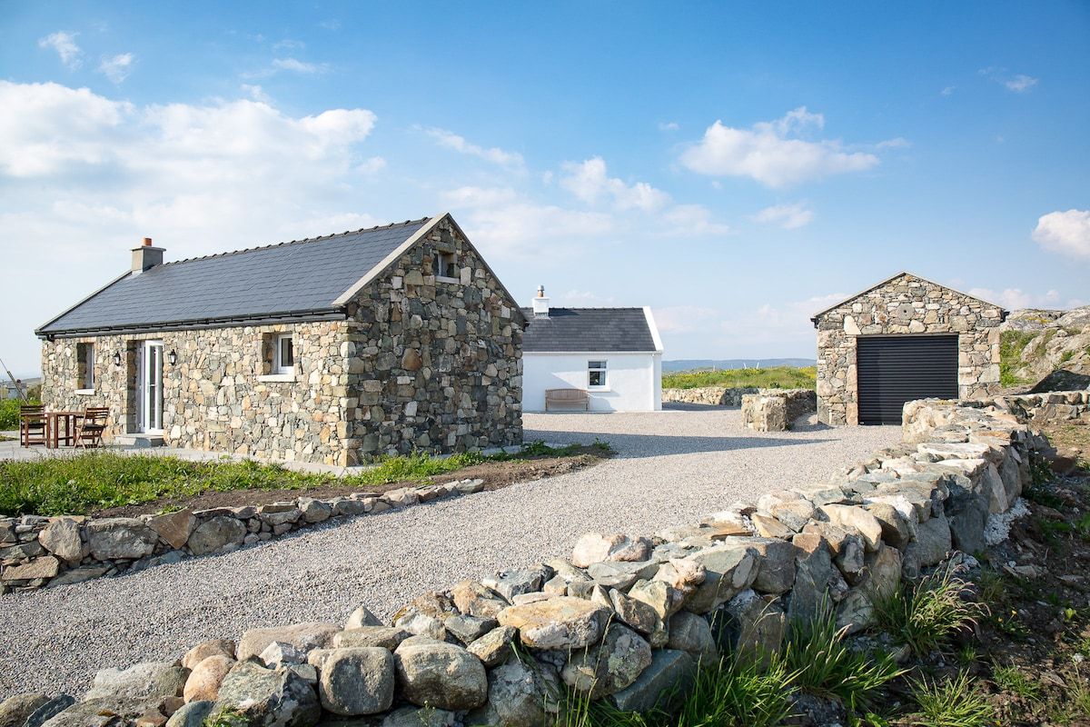 A stone house with a gravel driveway and a stone wall.
