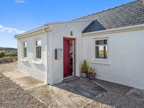 A white building with a red door, a small window, and a mailbox. - Paddy Carroll´s, Ballyconneely (Ballyconneely)