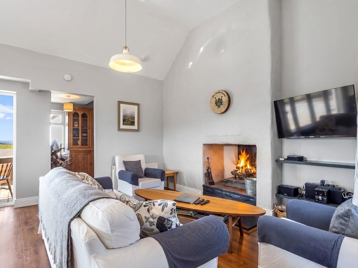 A modern living room with a fireplace, comfortable seating, and a television.