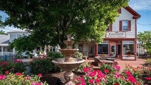A rustic building with a sign reading "Rustico Restaurant & Wine Bar" and a large outdoor fountain surrounded by vibrant flowers.
