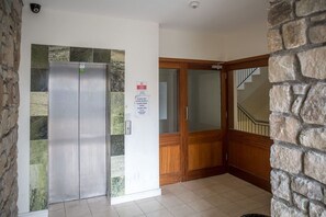 A hallway with a refrigerator, a door with a sign, and a staircase. - Robins Nest (Clifden)