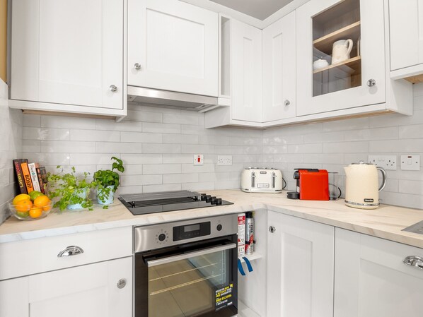 A modern kitchen with white cabinets, a built-in oven, a toaster, and a kettle. - Robins Nest birds eye view of Clifden town (Clifden)