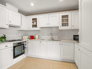 A modern kitchen with white cabinetry, a built-in oven, a microwave, and a sink. - Robins Nest (Clifden)
