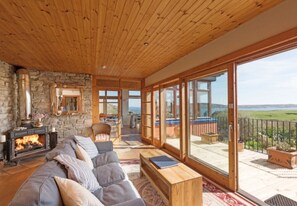 Un salón espacioso con chimenea, un sofá grande y un balcón con vistas al paisaje.