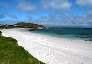 A beach with white sand, a grassy area, and a clear blue sky. - Rugosa Family House in Scenic Ballyconneely (Ballyconneely)