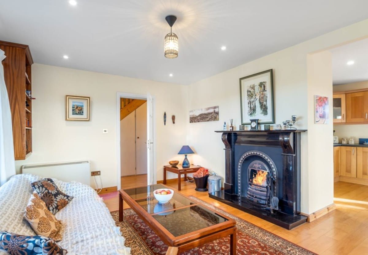 A living room with a fireplace, a sofa, a glass coffee table, and a rug.