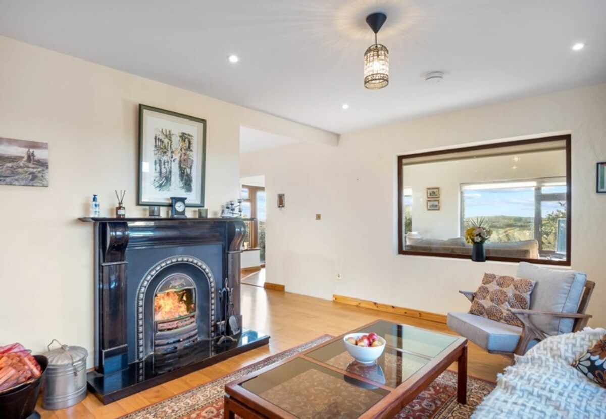 A living room with a fireplace, a sofa, a coffee table, and a large window.