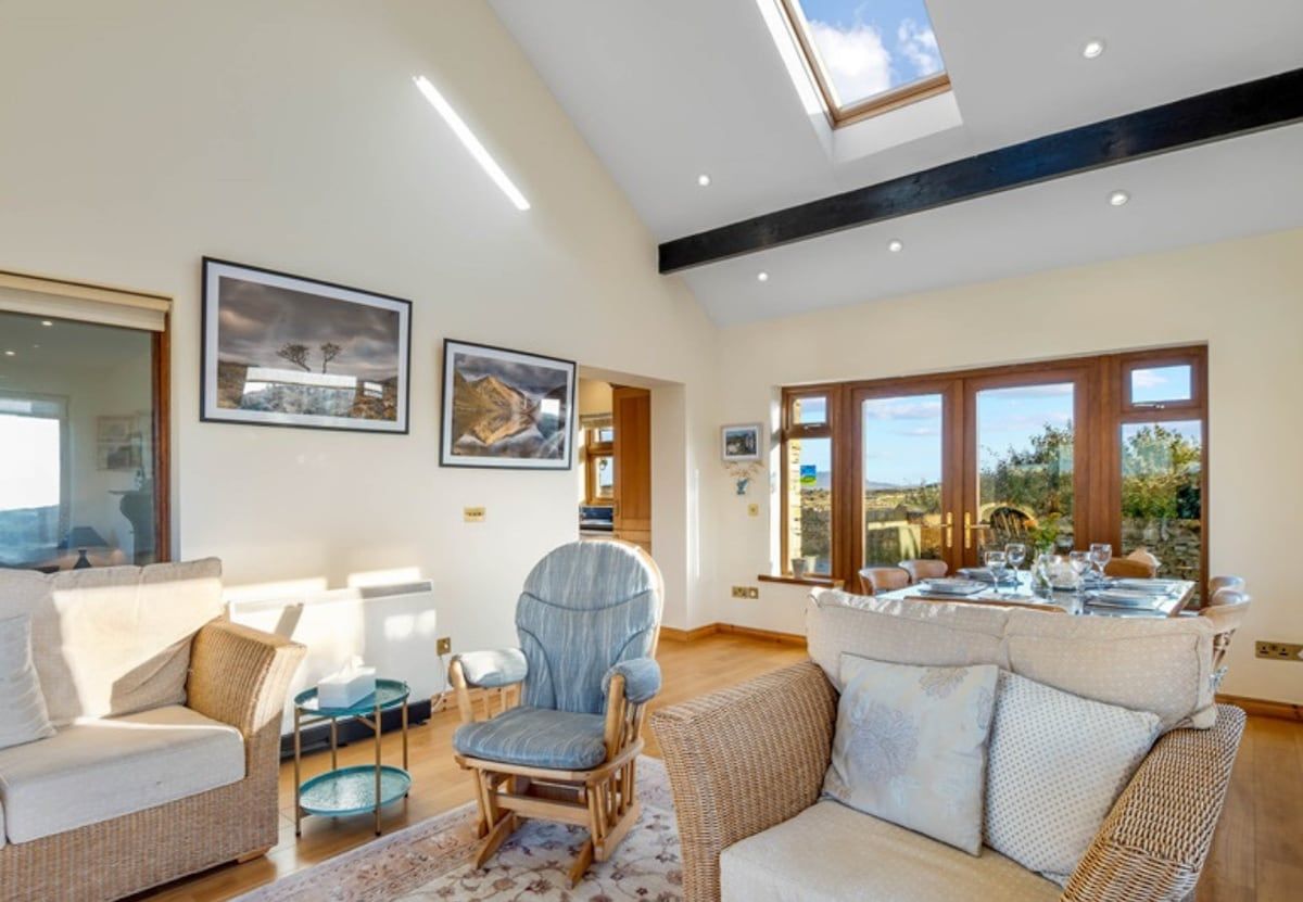 A spacious living room with a high ceiling, large windows, and a dining area.