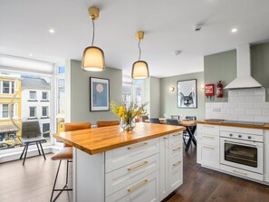 A modern kitchen with white cabinetry, a wooden countertop, and pendant lighting.