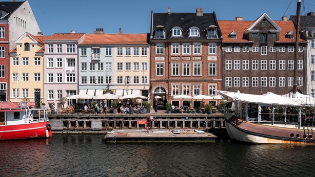 A canal with boats docked, a row of colorful buildings, and outdoor seating areas. - Nyhavn63 Suites 2 by Daniel&Jacob's (København)