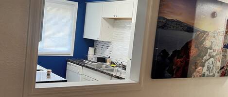 A kitchen with white cabinets, a stove, and a sink.